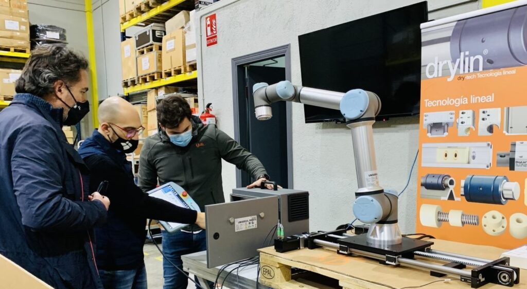 Equipo técnico de igus mostrando el 7º eje para el cobot de Universal Robots